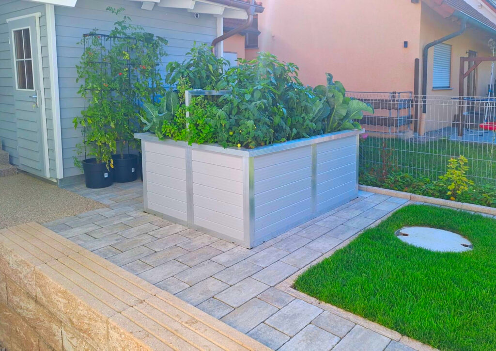 WAMA Hochbeet mit Aluminium-Paneelen und stark gewachsenen Gemüsepflanzen auf einer Terrasse