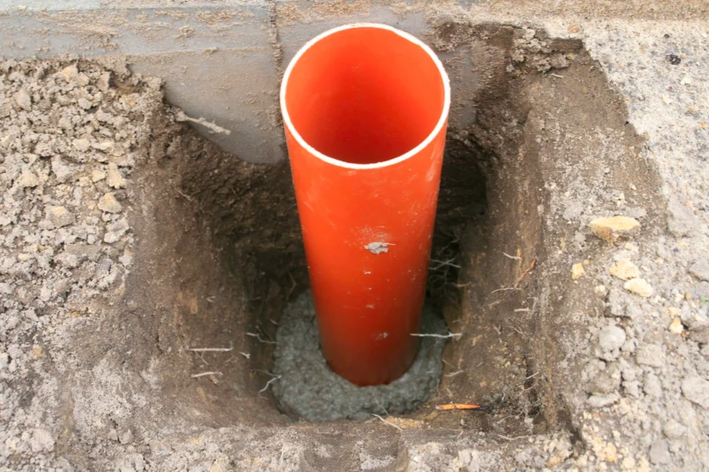 Orangerotes Leerrohr eines Punktfundaments, das am unteren Ende in Beton gesetzt wurde