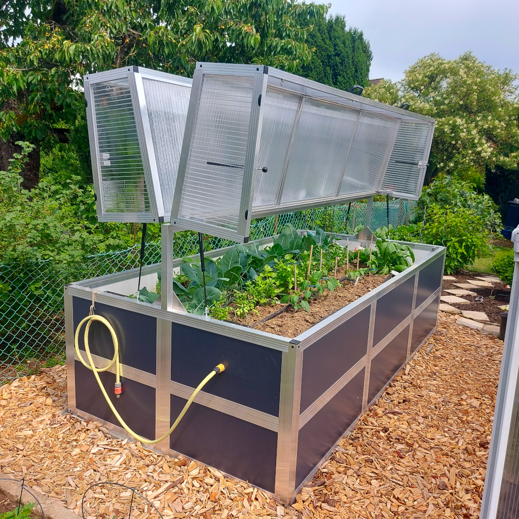 Großes Hochbeet aus Aluminium 150x300 cm mit anthrazitfarbenen Sandwichplatten, geöffnetem Frühbeet-Aufsatz und angeschlossenem Wasserschlauch im Garten