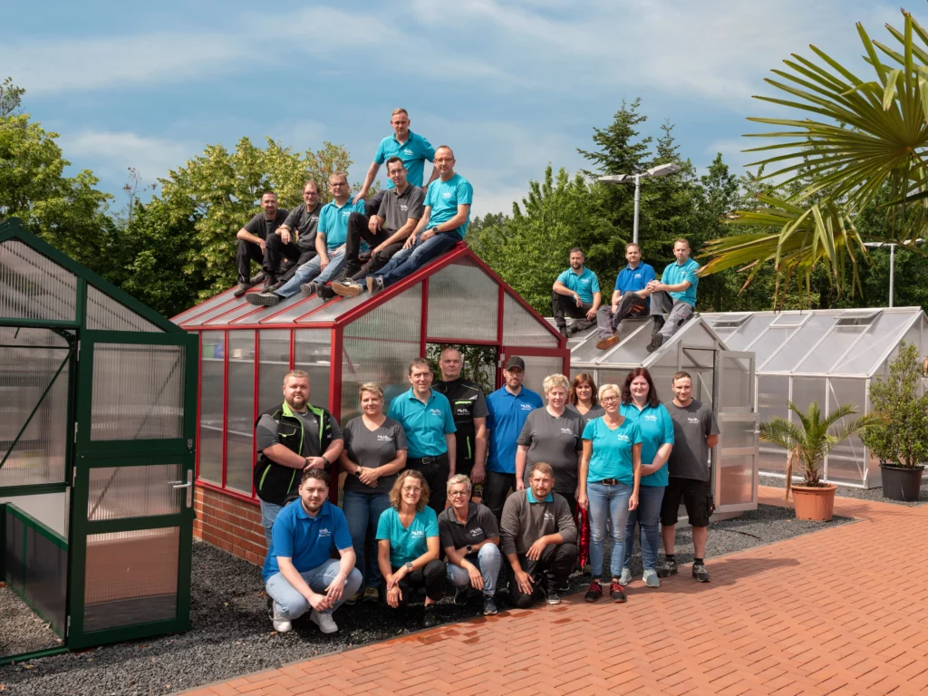 Das WAMA-Team steht und sitzt vor und auf den Gewächshäusern auf dem Firmengelände in Herdorf.