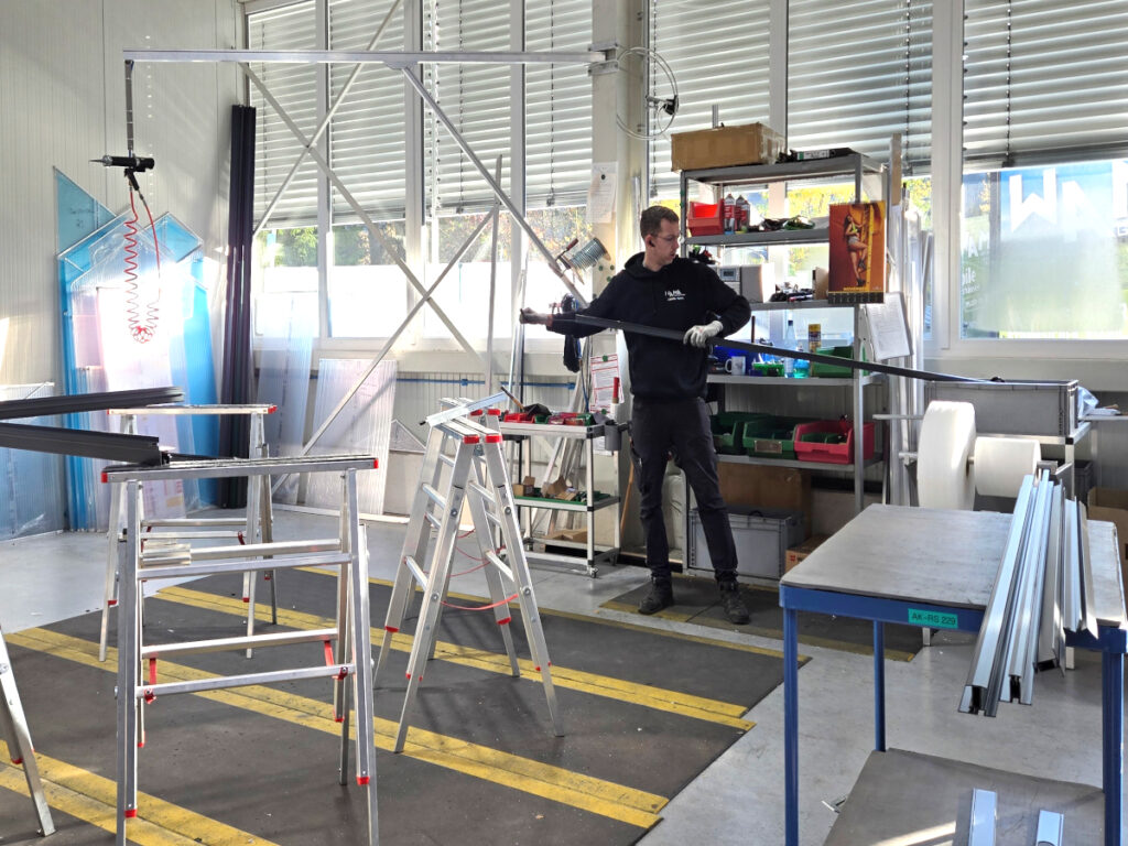 Ein WAMA-Kollege zieht die Türdichtung in einen pulverbeschichteten Türpfosten aus Aluminium ein.